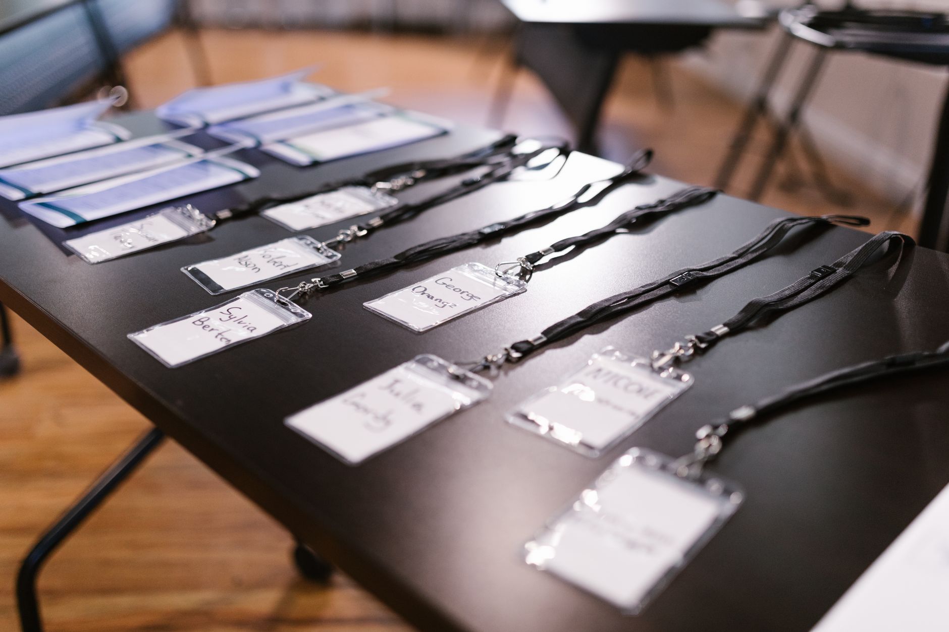 Name tags, lanyards and folders laid out in rows on a check-in table before an event opens.